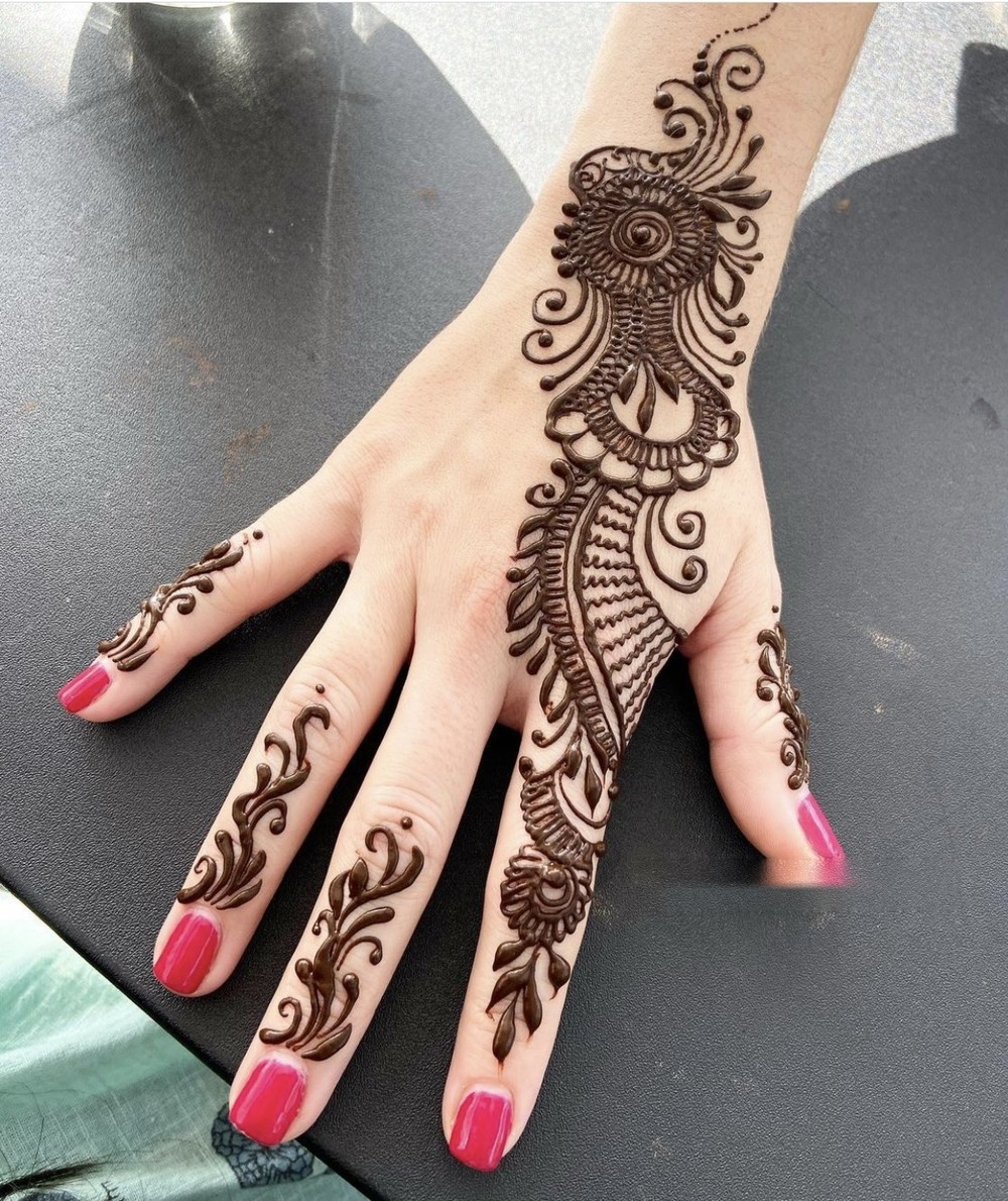 Detailed feather and mandala henna design on the back of a hand