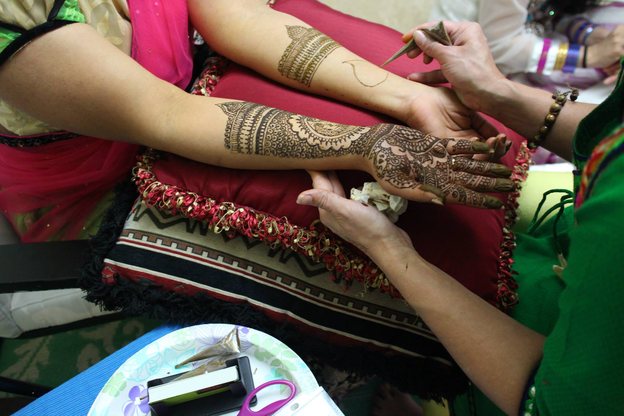 Close-up of henna artist applying intricate mehndi design on hand during private appointment